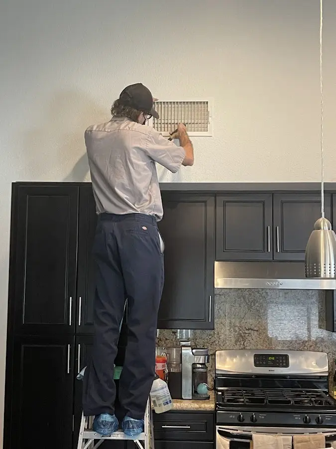 Technician inspecting an air vent during HVAC service in Old Orchard Beach